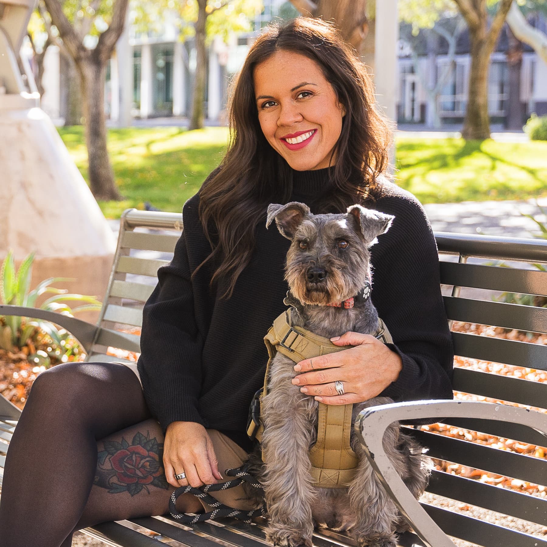 Sydney Martinez sitting on a park bench holding a gray schnauzer